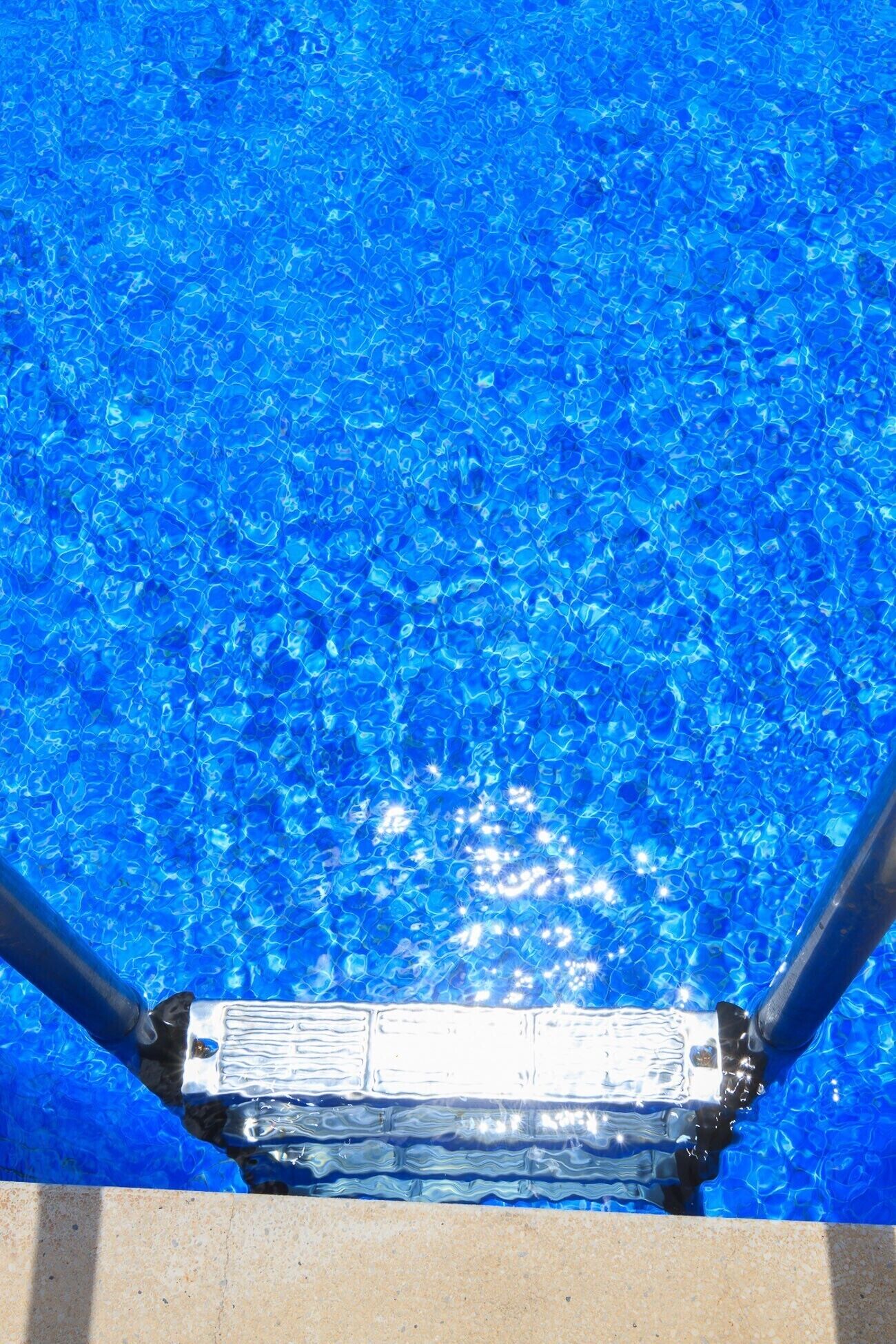A swimming pool with clear blue water and a metal ladder.