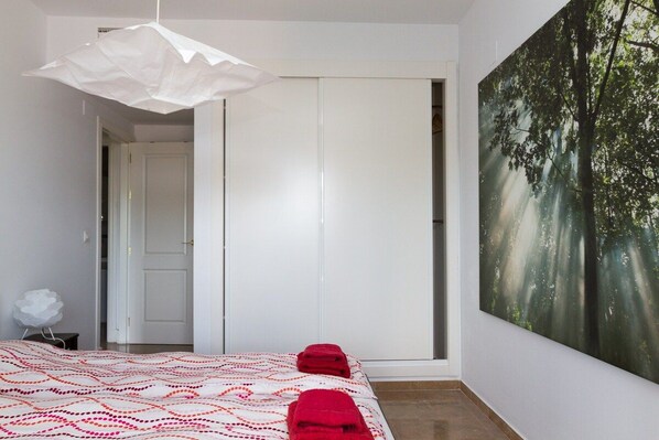 A bedroom with a bed, a white door, and a large forest-themed wall mural.