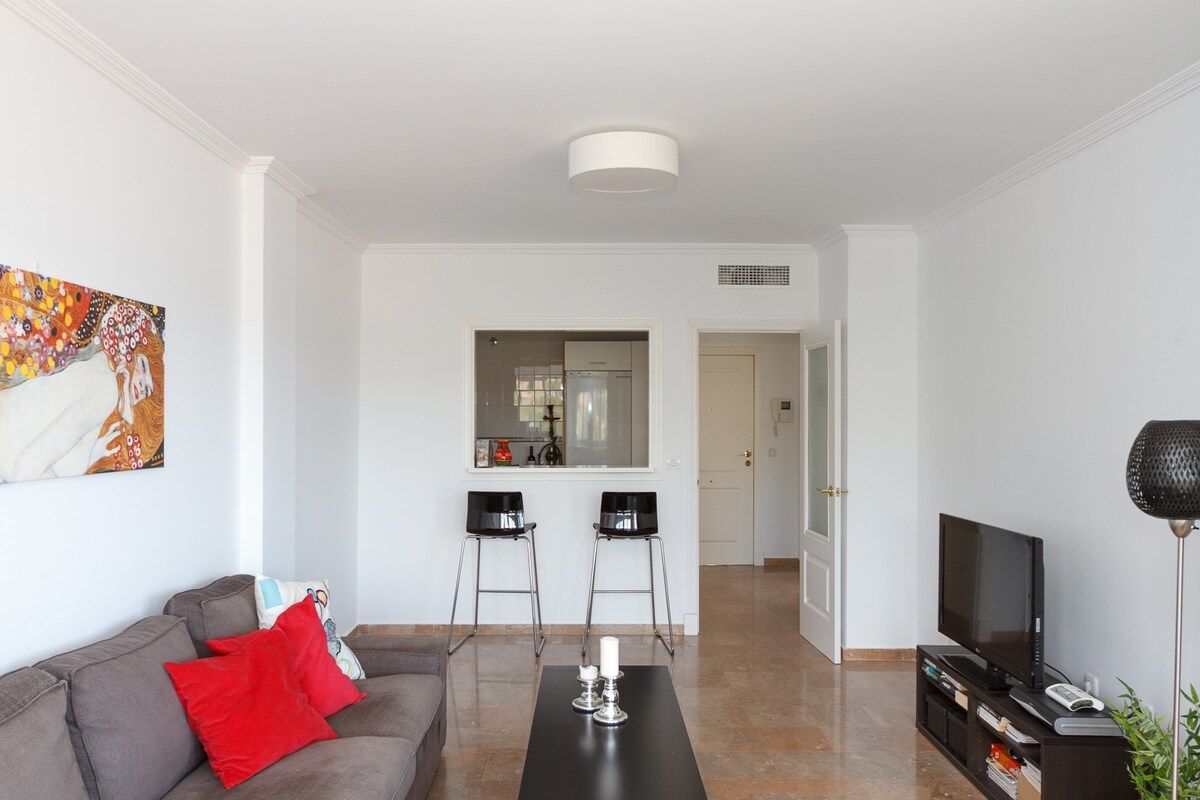 Ein modernes Wohnzimmer mit einer Couch, einem Couchtisch, einem Fernseher und einem Bild an der Wand.