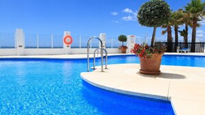 A swimming pool with a clear blue water, a lifebuoy, and a potted plant with flowers. - Puerta del Mar - Direct access to the beach (Mijas Costa)