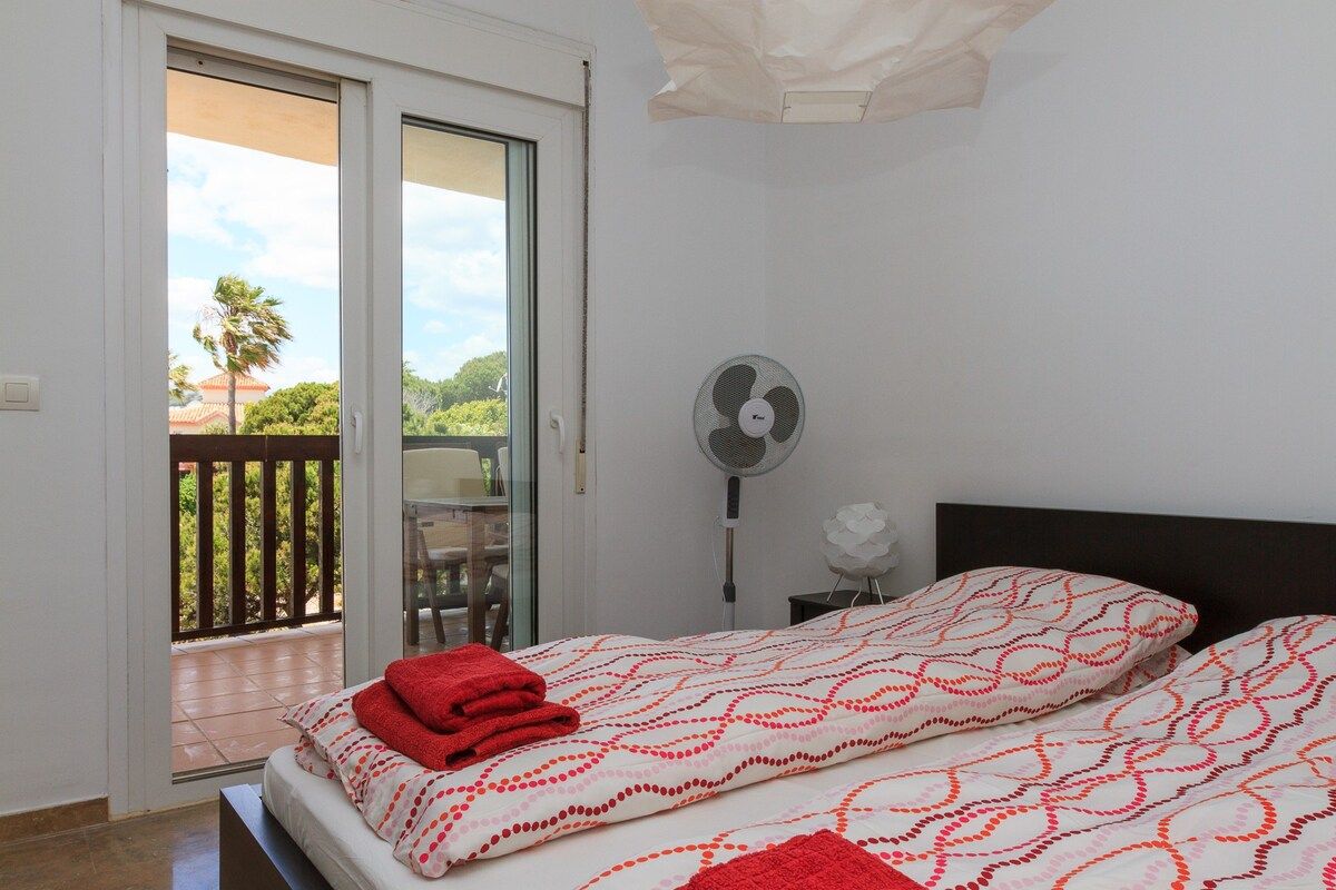 Une chambre à coucher avec un lit, un ventilateur et une vue sur l’extérieur.