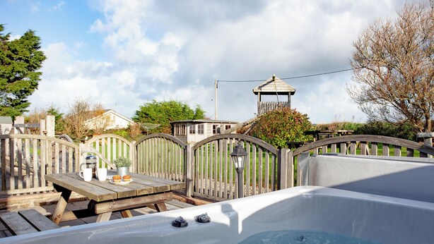 Un bain à remous avec une terrasse en bois et une clôture.