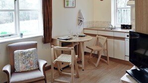 Una cocina compacta con una mesa de comedor, sillas, un televisor y una ventana con cortinas.