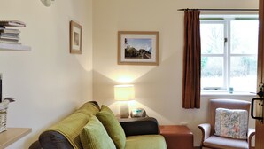 Una sala de estar acogedora con un sofá, una silla, una lámpara y una ventana con cortinas.