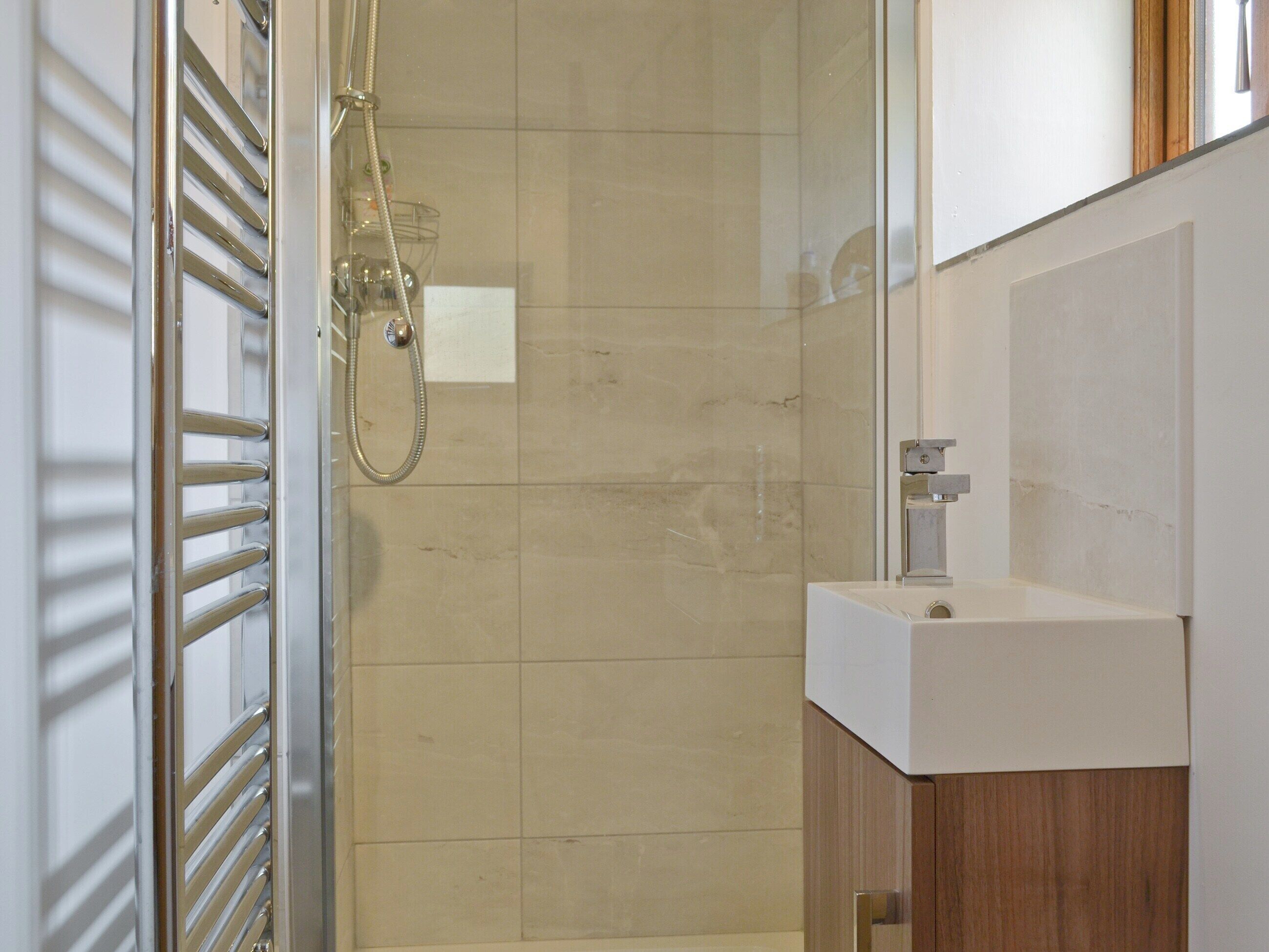 Un baño moderno con cabina de ducha de vidrio, un lavabo blanco y un mueble de madera.