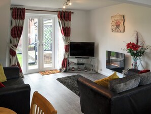 A living room with a TV, sofa, and a decorative sign on the wall.