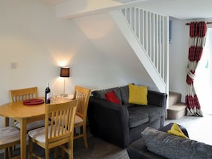 A modern living space with a dining area, a sofa, and a staircase. - 1 bedroom accommodation in Wroxham (Wroxham)
