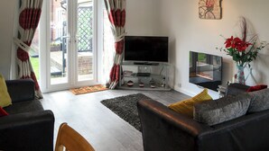 Uma sala de estar com televisão, sofá e um letreiro decorativo na parede.