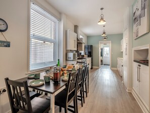 Une cuisine moderne équipée d’une table à manger pour quatre personnes, d’une cuisinière, d’un four à micro-ondes et de placards.
