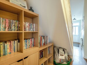 A wooden bookshelf filled with books, a green bag, and a framed picture on the top shelf.