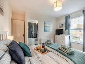 Een slaapkamer met een bed, nachtkastje en een raam met gordijnen.