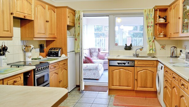 A kitchen with wooden cabinets, a dishwasher, a stove, and a dining area with a table.