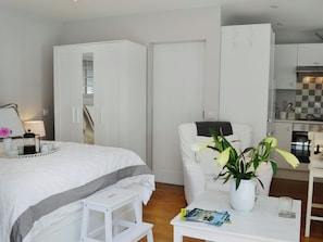A bedroom with a bed, bedside table, and a chair with a plant. - 1 bedroom accommodation in Cuckfield, near Haywards Heath (Cuckfield, near Haywards Heath)