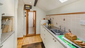 A compact kitchen with a skylight, a sink, and a countertop with bread.