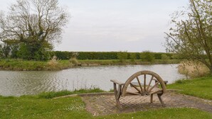 A riverside park with a wooden bench and a large wheel structure. - Carp Cottage - UKC1907 (Doddington, near Lincoln)
