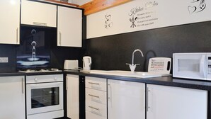 Une cuisine moderne avec des armoires blanches, un four encastré, un four à micro-ondes et une machine à café.