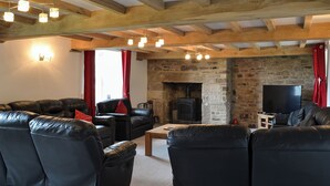 Una sala de estar acogedora con chimenea de piedra, sofás de cuero y un televisor de pantalla plana.