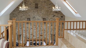Una habitación con pared de piedra, barandilla de madera y tragaluz.