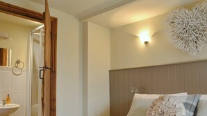 A bedroom with a bed, a bedside table, a wall-mounted light fixture, and a decorative wall piece. - The Cottage at Wilson House (Barningham, near Richmond)