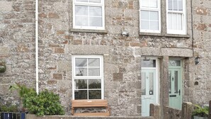 A stone building with three windows, a door, and a bench. - 3 bedroom accommodation in The Lizard Village, near Helston (The Lizard Village, near Helston)