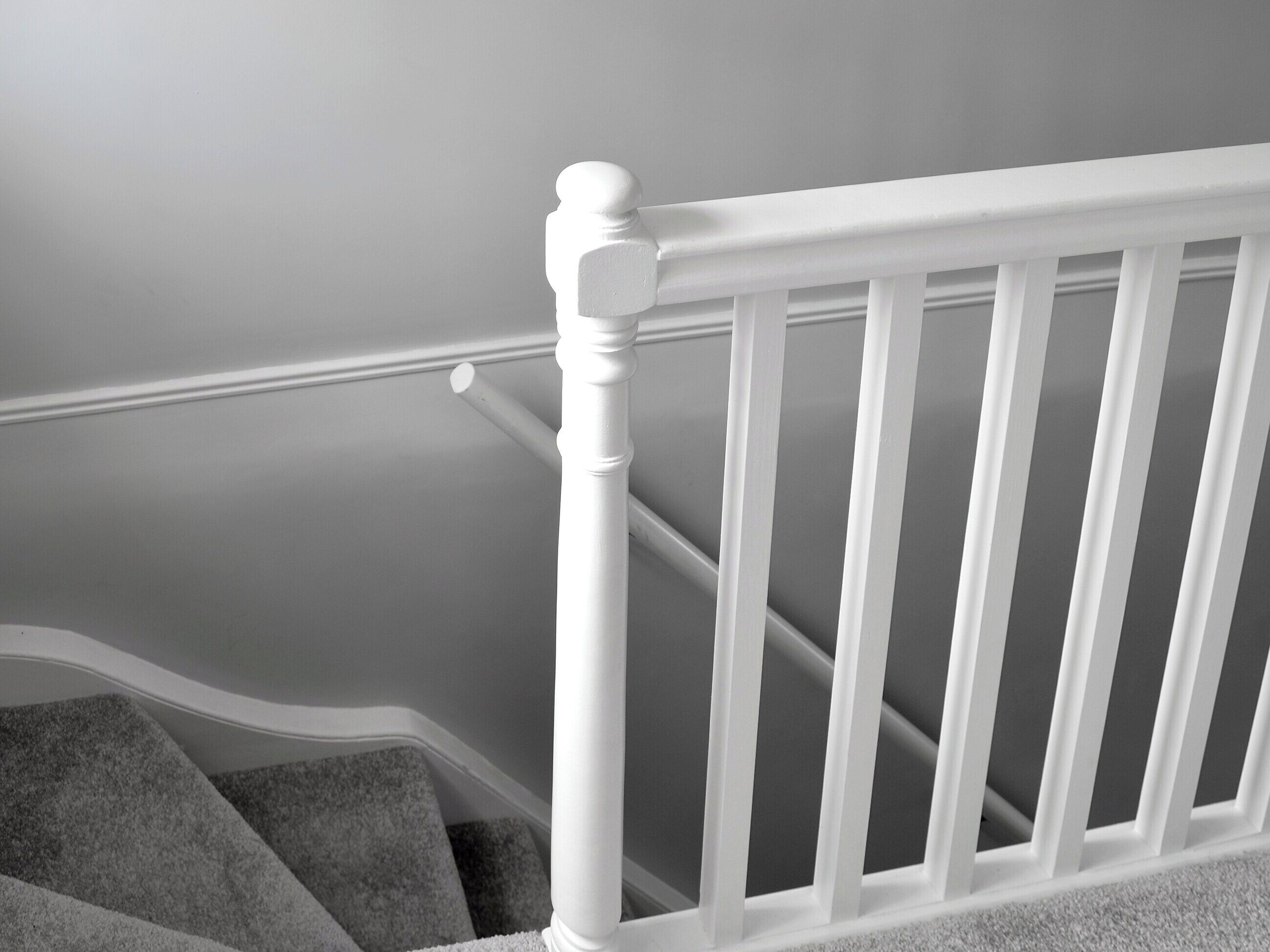 A white wooden staircase with a handrail and carpeted steps.