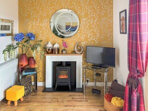 Ein Wohnzimmer mit Kamin, Fernseher und gelbem Blumenwallpaper.