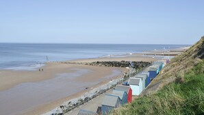 Une plage bordée d’une rangée de cabanes de plage aux couleurs vives.