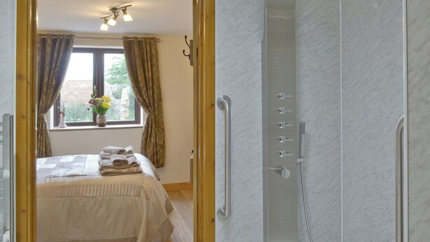 Een badkamer met een douche, een bed met handdoeken, en een raam met gordijnen.