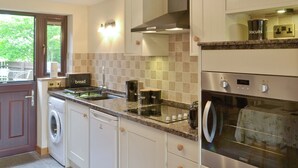 Een moderne keuken met een inbouwoven, een wasmachine en een koffiezetapparaat.