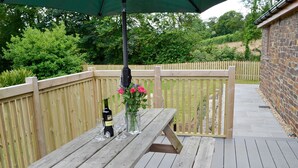A wooden deck with a picnic table, a bottle of wine, and a vase with flowers. - 2 bedroom accommodation in Bodmin (Bodmin)