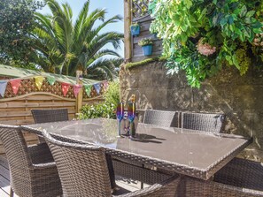 An outdoor patio with wicker furniture, a glass table, and potted plants. - 2 bedroom accommodation in Ventnor (Ventnor)