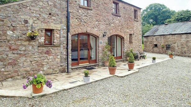 A stone building with a gravel driveway and potted plants. - 1 bedroom accommodation in Bleatarn, near Kirkby Stephen (Bleatarn, near Kirkby Stephen)
