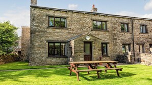 A stone farmhouse with a wooden picnic table in the yard. - 4 bedroom accommodation in Hawes (Hawes)