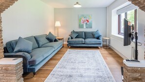 A living room with two sofas, a rug, a painting, a lamp, and a TV. - 4 bedroom accommodation in Hawes (Hawes)
