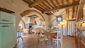 A rustic kitchen with a round wooden table, white chairs, and a vintage refrigerator. - VILLA MERAVIGLIOSA - Six Bedroom Villa, Sleeps 12 (Pienza)