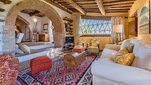 A cozy living room with a fireplace, a large window, and a patterned rug. - VILLA MERAVIGLIOSA - Six Bedroom Villa, Sleeps 12 (Pienza)