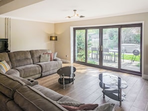A living room with a sectional sofa, a glass-top coffee table, and a sliding glass door leading to an outdoor patio.