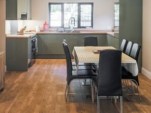 Cozinha moderna com área de refeições, piso de madeira e vista para o exterior.