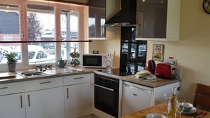 Cocina compacta con lavamanos, microondas, estufa y comedor con una mesa lista para dos personas.