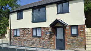 A two-story building with a stone facade, a black door, and a sign reading "Knight's Den". - 2 bedroom accommodation in Port Isaac (Port Isaac)