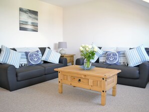 A living room with a dark grey sofa, striped pillows, a wooden coffee table, and a vase with flowers.