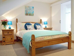 A bedroom with a wooden bed, two bedside tables, a nightstand, a wall-mounted painting, and a window. - 2 bedroom accommodation in Hartland, near Bideford (Hartland, near Bideford)