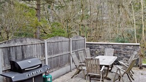 An outdoor patio with a grill, chairs, and a table.