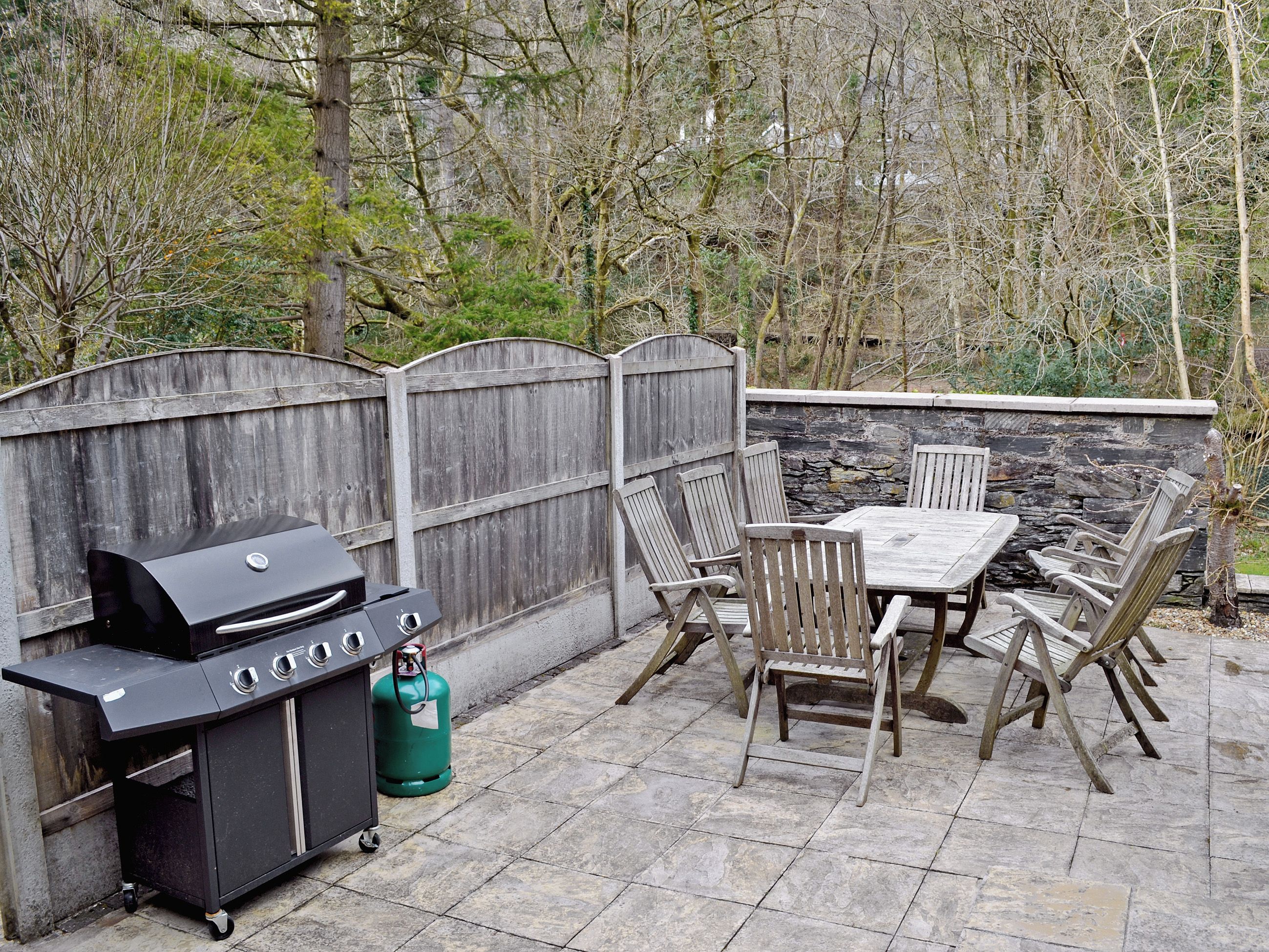 Une terrasse extérieure avec un barbecue, des chaises et une table.