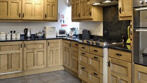 A kitchen with wooden cabinets, a stove, a refrigerator, and a coffee maker.