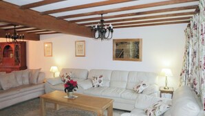Un salon avec un canapé, une table basse en bois, un lustre et une cheminée.
