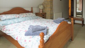 Une chambre à coucher avec un lit en bois, une literie à motifs floraux, un mur en pierre, un radiateur et un miroir.