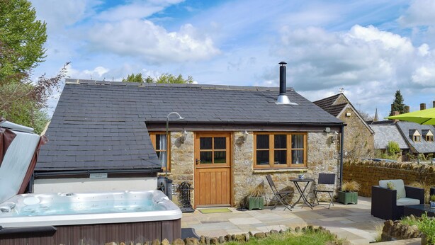 A stone house with a wooden door, a hot tub, and outdoor furniture. - 1 bedroom accommodation in Swerford, near Chipping Norton (Swerford, near Chipping Norton)