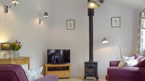 A living room with a TV, a fireplace, and two purple sofas. - 1 bedroom accommodation in Swerford, near Chipping Norton (Swerford, near Chipping Norton)