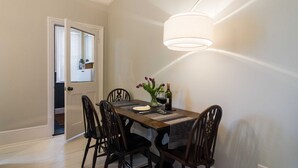 Un coin repas avec une table en bois, six chaises, un vase avec des fleurs et une bouteille de vin.